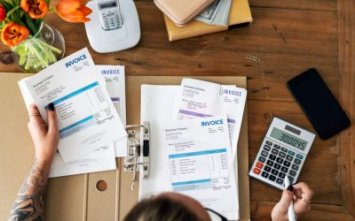 Personne examinant des documents financiers et gérant des factures impayées avec une calculatrice.