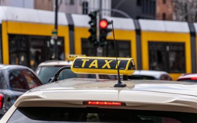 Taxi blanc stationné dans une rue urbaine avec feu rouge et tramway jaune derrière