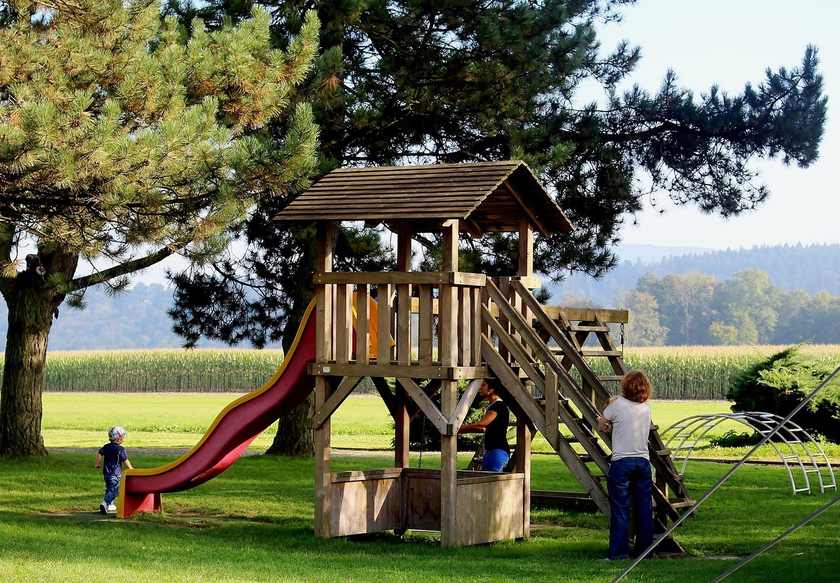 Enfants jouant sur un toboggan rouge et une structure en bois dans un parc Enfants jouant sur un toboggan rouge et une structure en bois dans un parc