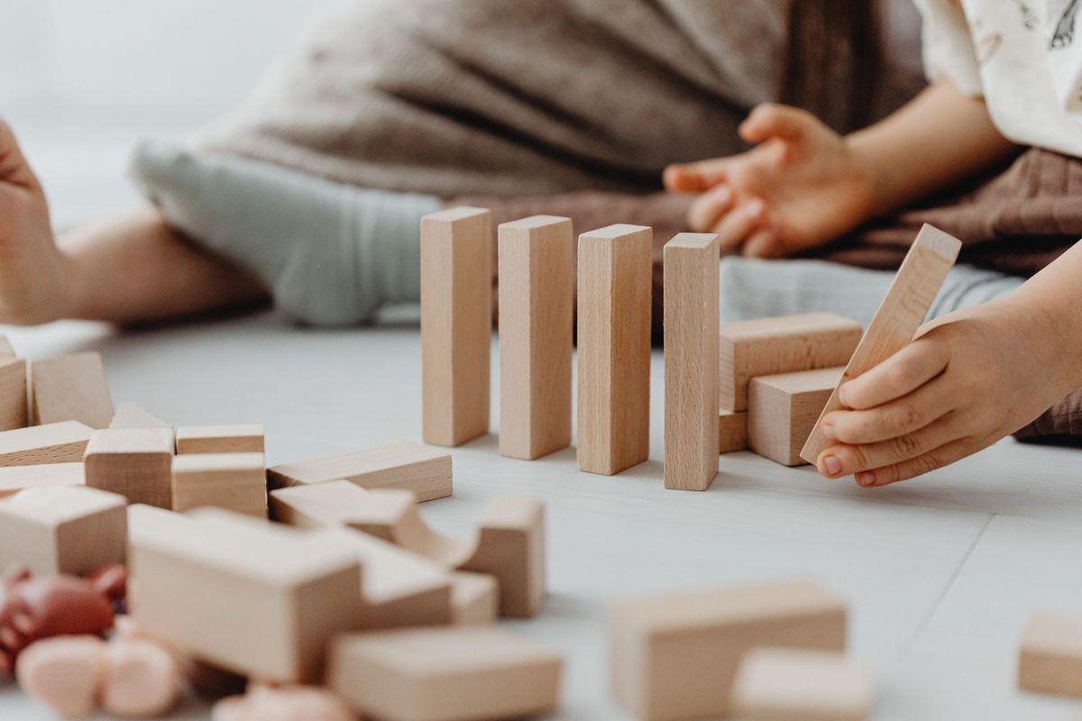 Enfant manipulant des blocs en bois, une pile et un bloc en main Enfant manipulant des blocs en bois, une pile et un bloc en main