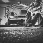 Un homme travaille sous une Volkswagen vintage dans un garage