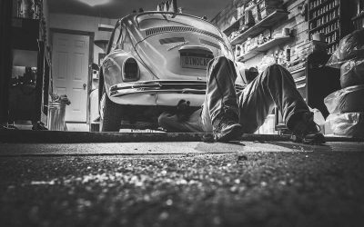 Un homme travaille sous une Volkswagen vintage dans un garage