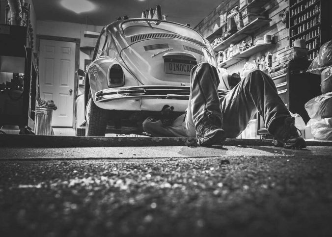 Un homme travaille sous une Volkswagen vintage dans un garage