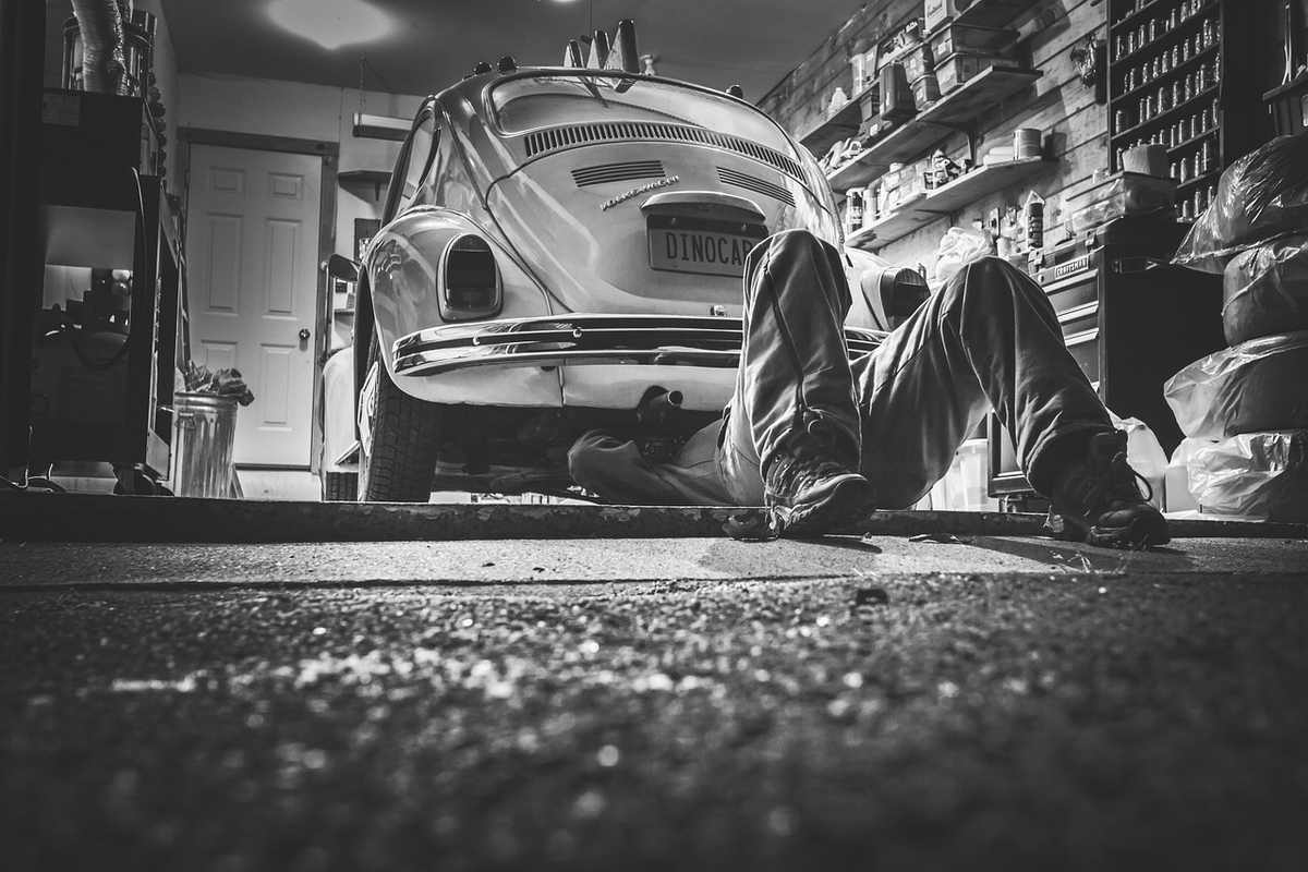 Un homme travaille sous une Volkswagen vintage dans un garage