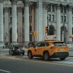 Taxi jaune et voiture noire devant un édifice monumental avec colonnes