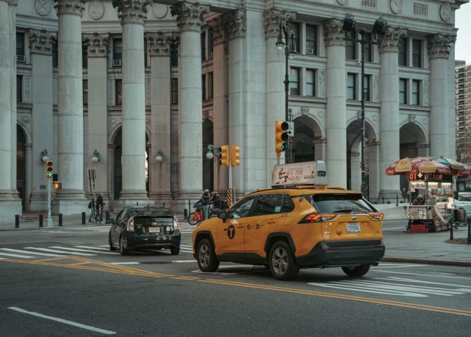 Taxi jaune et voiture noire devant un édifice monumental avec colonnes