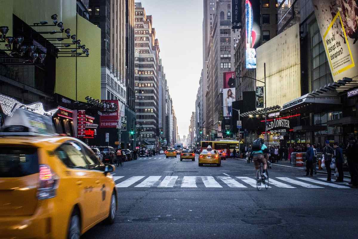 Avenue animée avec taxis jaunes, piéton, cycliste et bâtiments