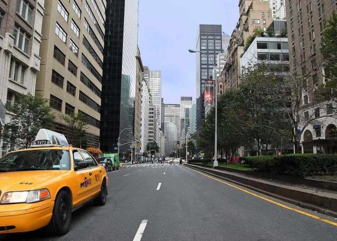 Rue de Manhattan avec taxi jaune stationné, immeubles de hauteur variée et arbres en arrière-plan