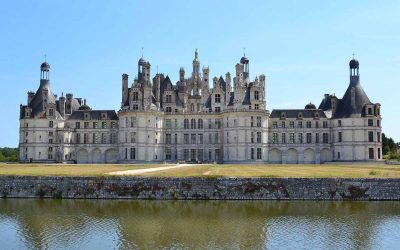 Un château Renaissance se reflète dans l'eau sous un ciel clair