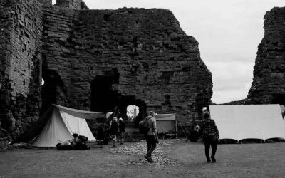 Tentes blanches dressées face aux ruines imposantes d'un château médiéval