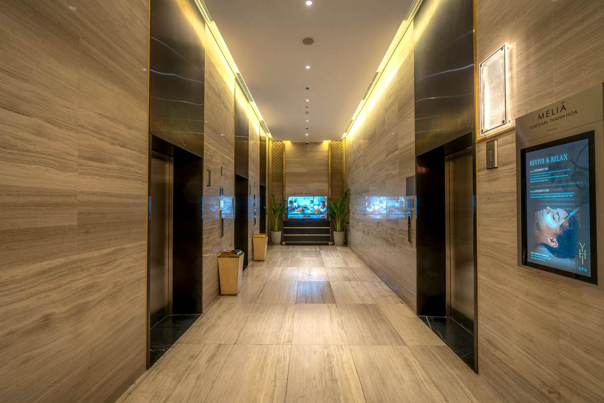 Hall d'hôtel moderne avec ascenseurs, sol en bois, écran et éclairage doux Hall d'hôtel moderne avec ascenseurs, sol en bois, écran et éclairage doux